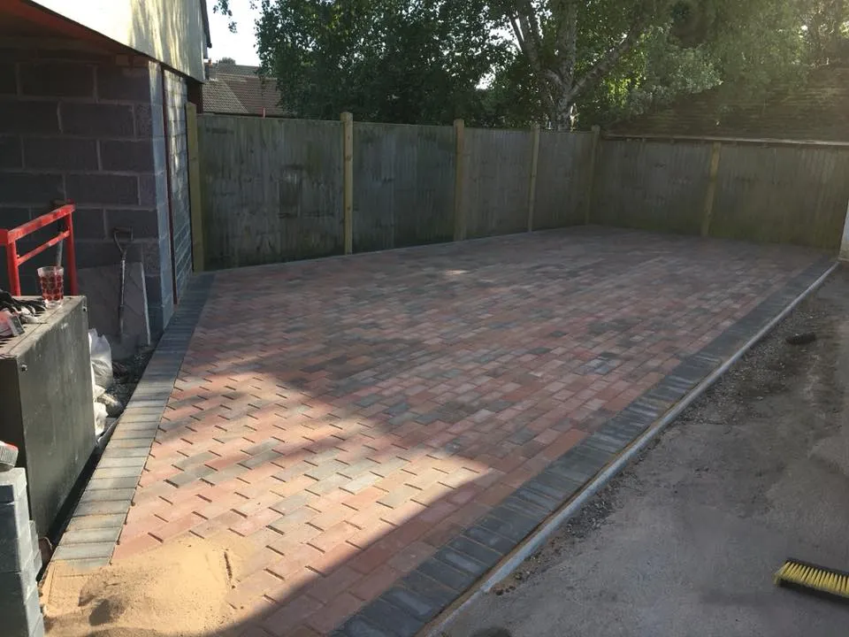 A brick patio being built in a backyard.