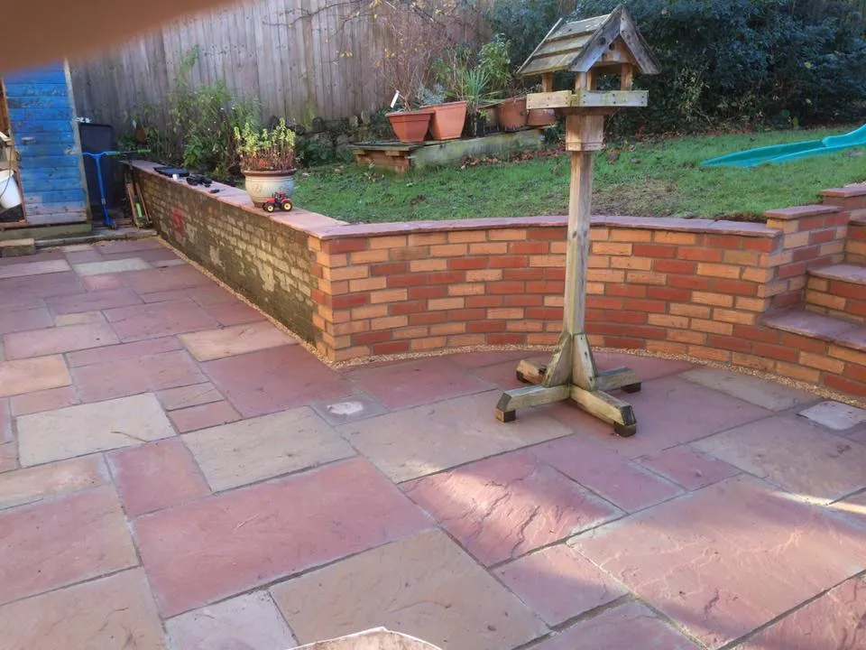 A garden with a brick wall and a bird house.
